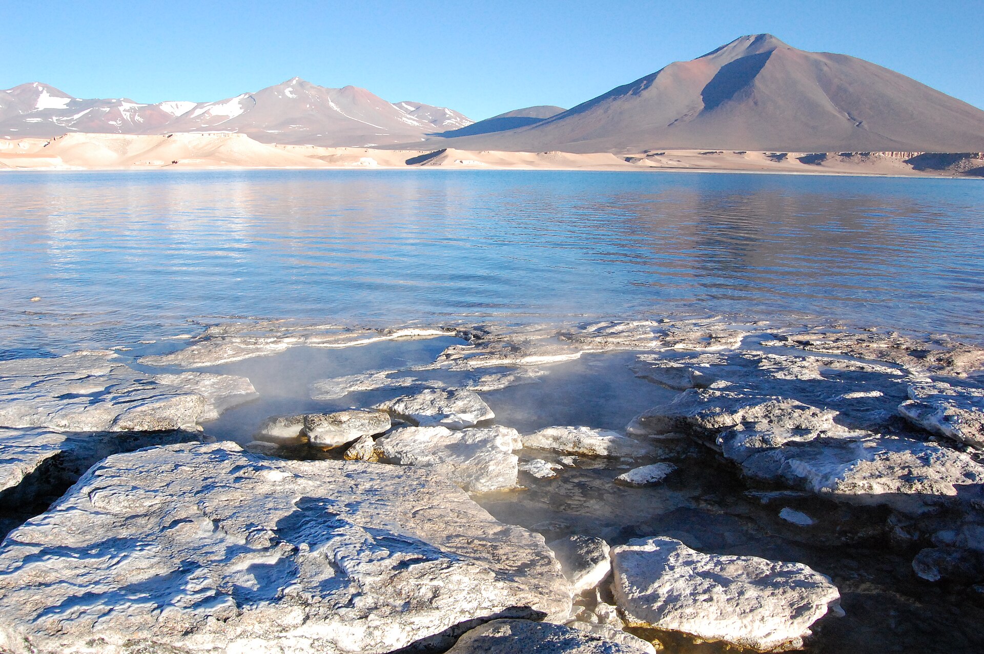 Laguna Verde, en el altiplano de Atacama, con termas humeantes en primer plano y volcanes al fondo