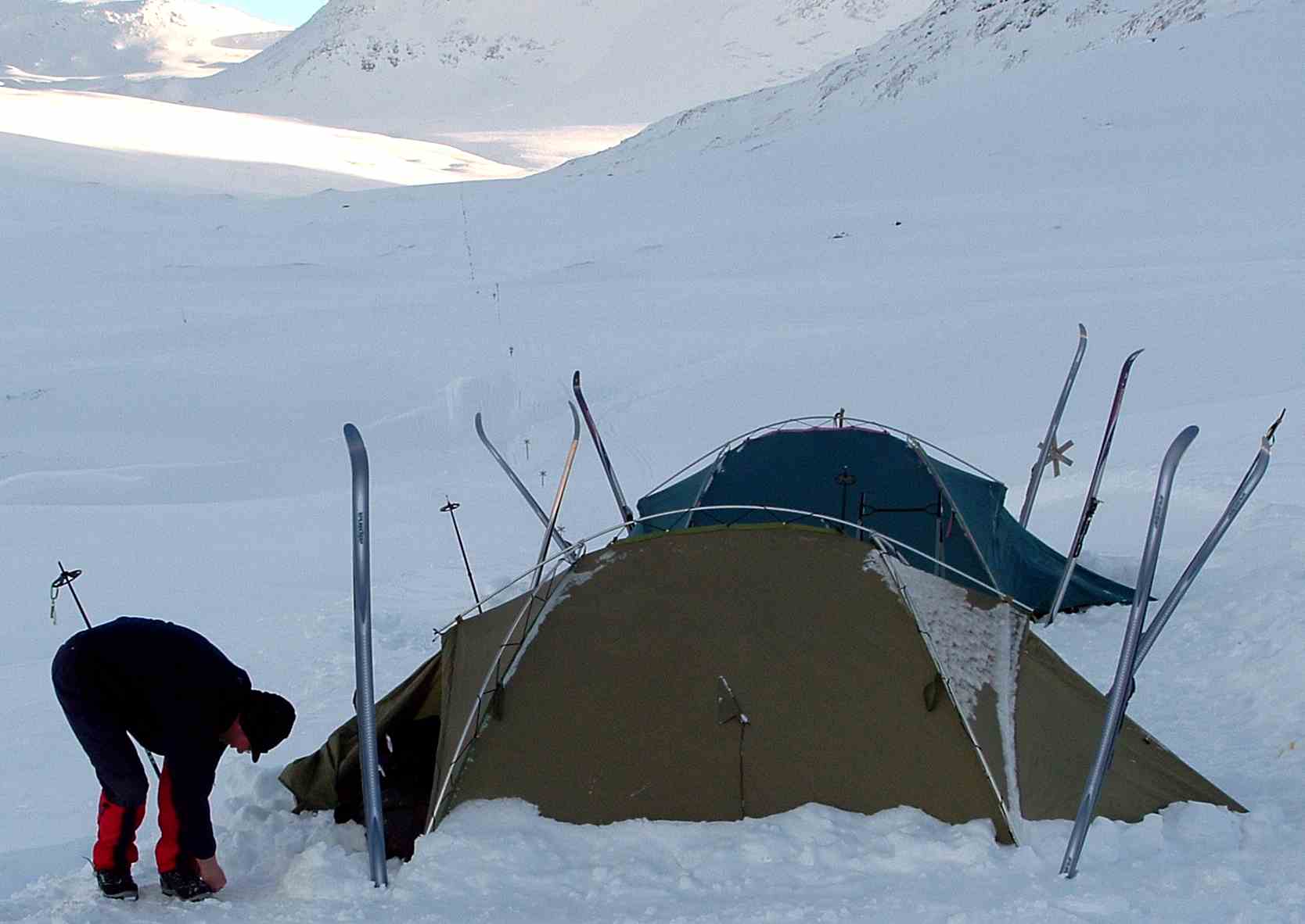 Campamento de dos tiendas dug en la nieve con esquís clavados alrededor, en las montañas de Suecia