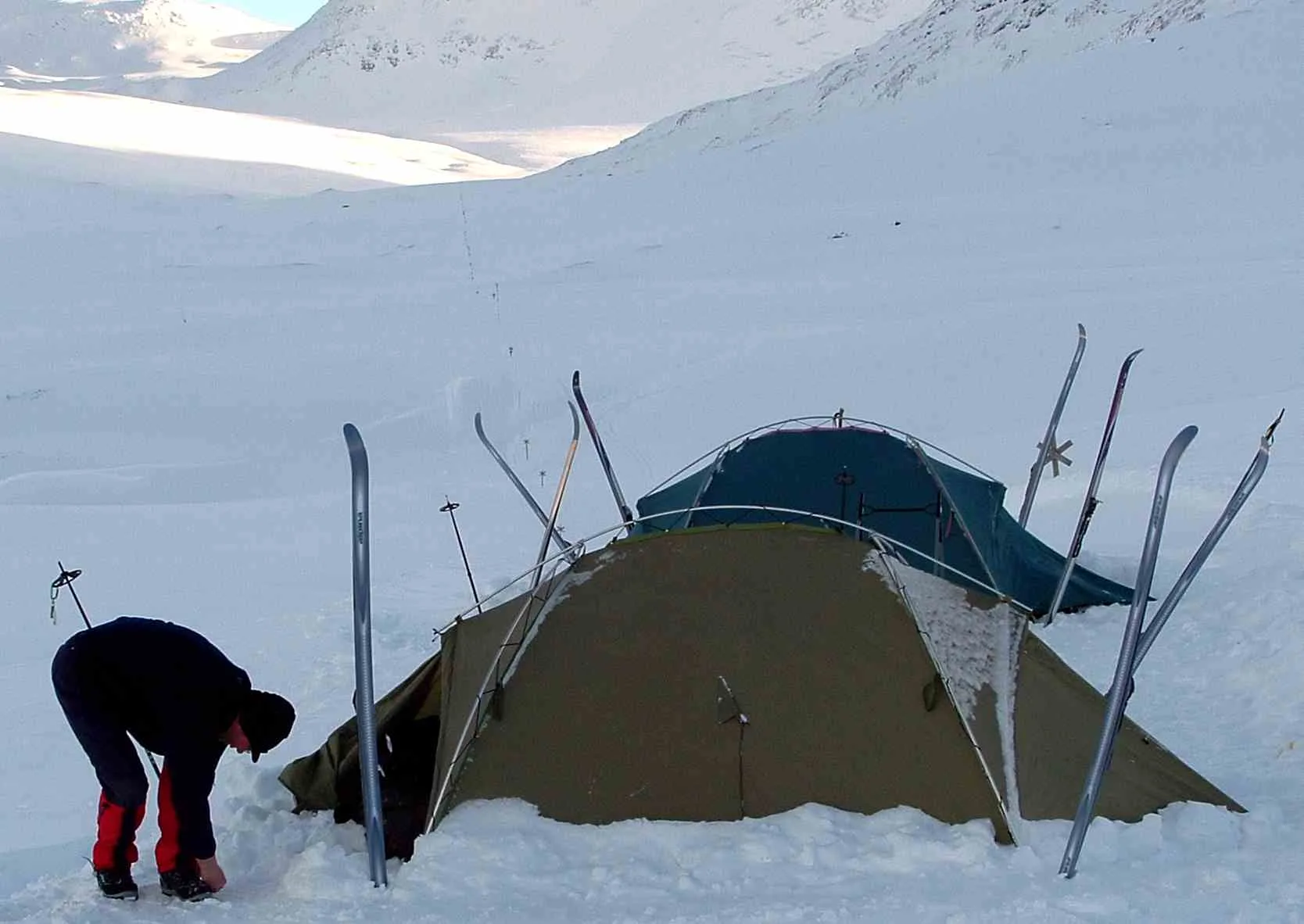 Montaña de un campamento de travesía en la nieve, con esquís clavados alrededor