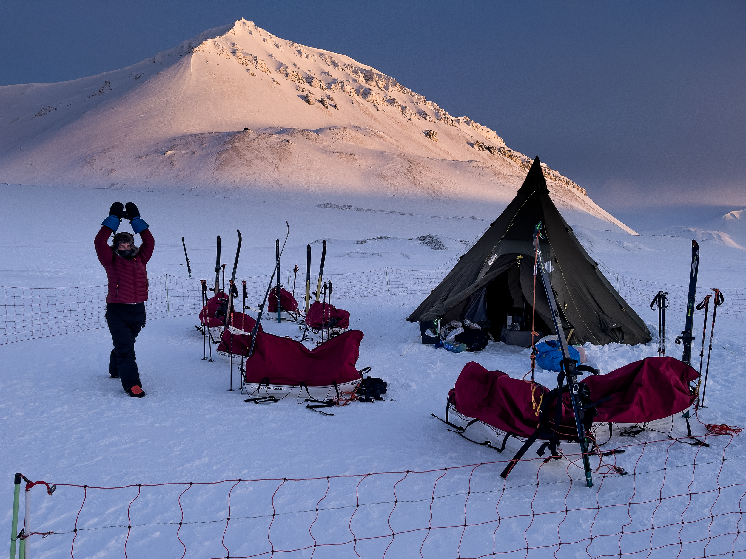 Campamento de expedición con tiendas y trineos al atardecer en Svalbard
