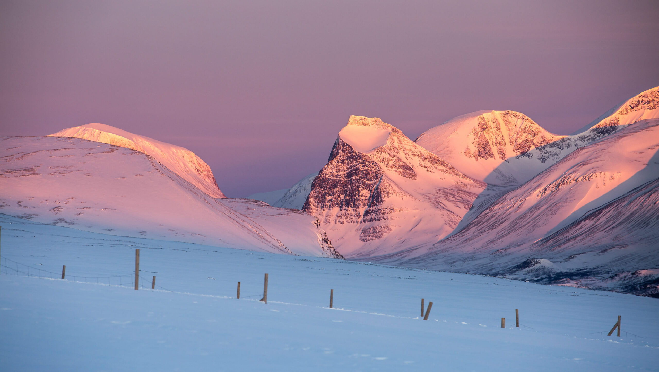 Luz de alpenglow sobre picos árticos nevados en Laponia