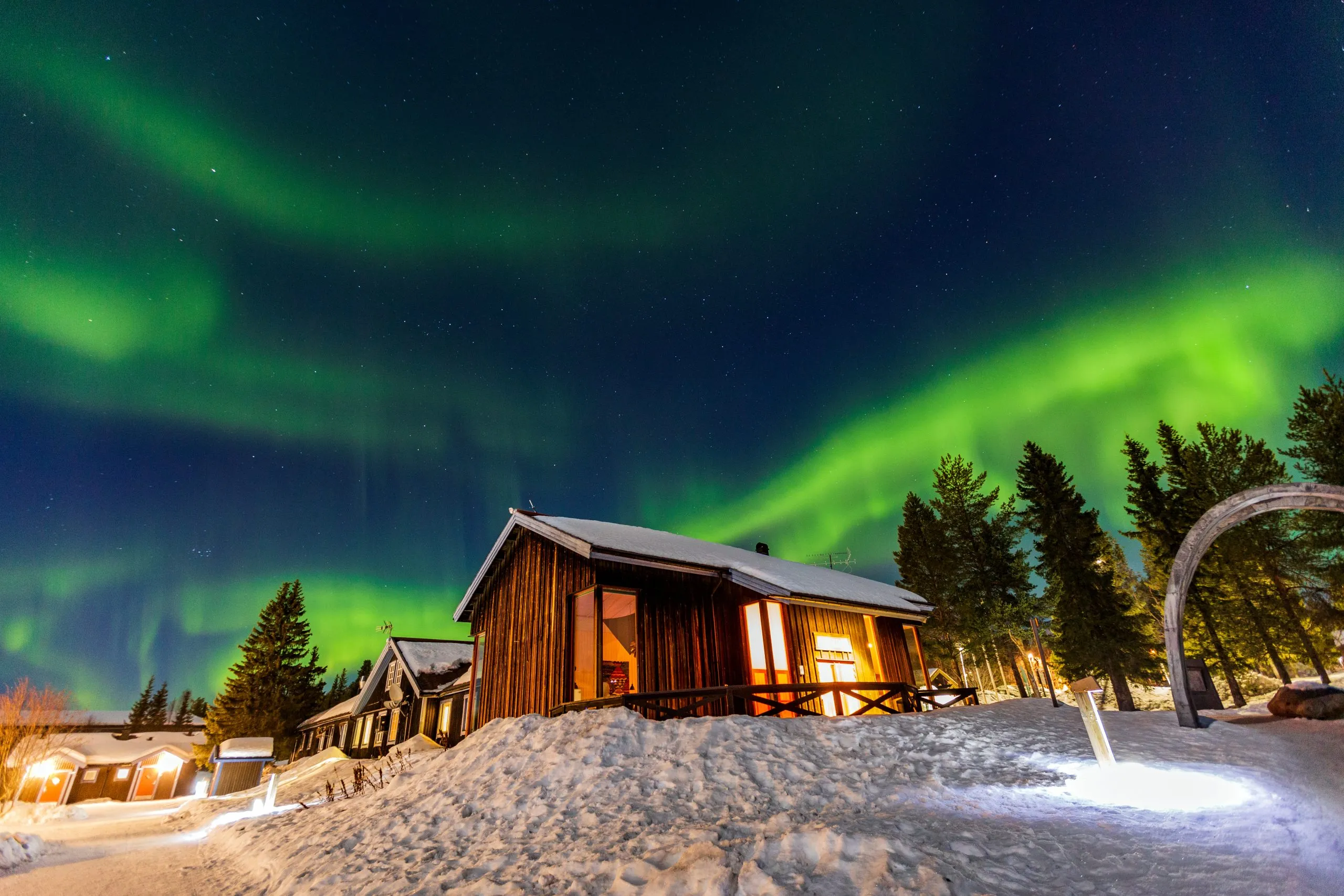 Aurora boreal sobre una cabaña de madera en Abisko, Laponia sueca