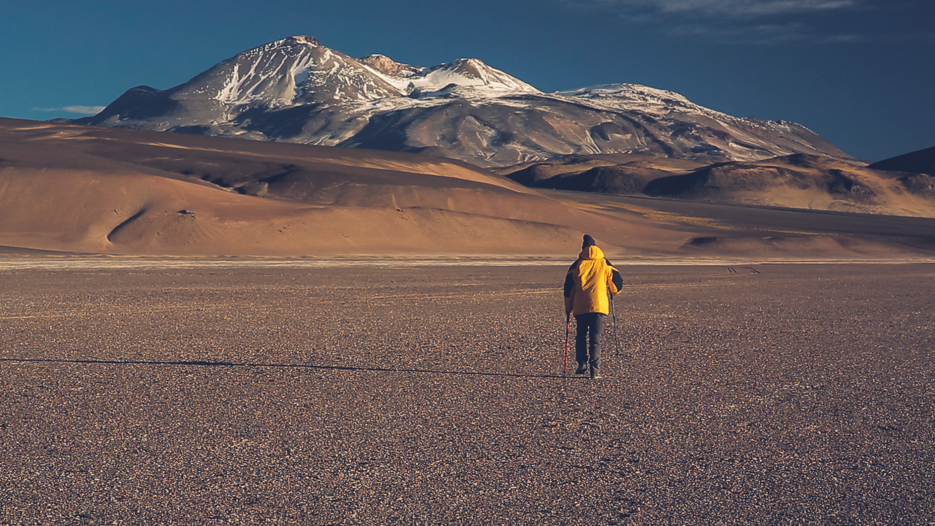 Montañista caminando por el desierto de Atacama frente al Ojos del Salado